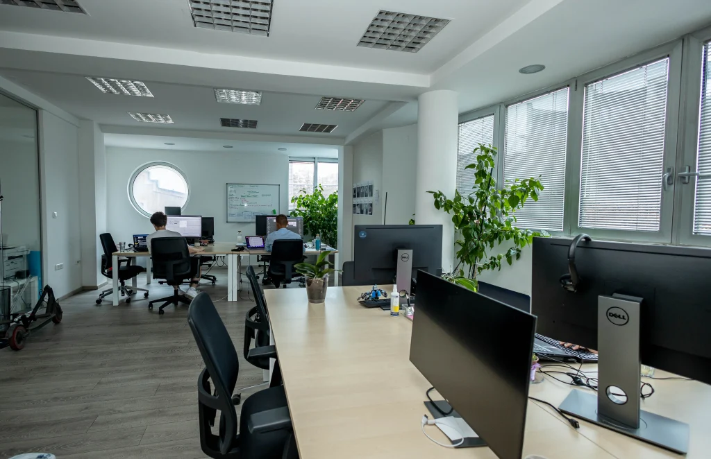 A vibrant open office space with vacant desks and software engineers working in the back